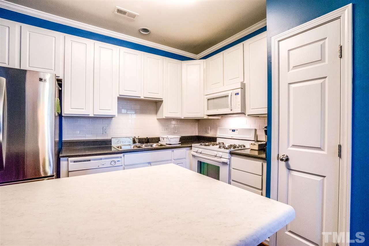 11710 Coppergate Drive, Unit 105 Raleigh, NC 27614 - Photo 10 of 24 a kitchen with stainless steel appliances granite countertop a stove a refrigerator a sink and white cabinets with wooden floor