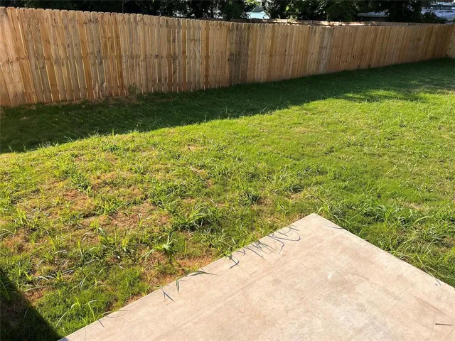 a view of backyard with wooden fence