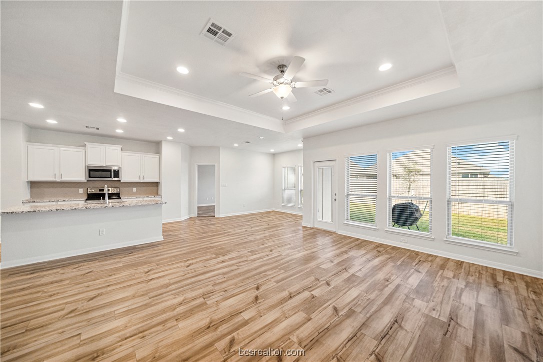 2018 Brisbane Way Bryan, TX 77807 - Photo 21 of 39 a view of an empty room with wooden floor and a kitchen