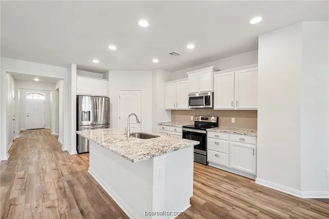 a large kitchen with kitchen island a sink stainless steel appliances and cabinets