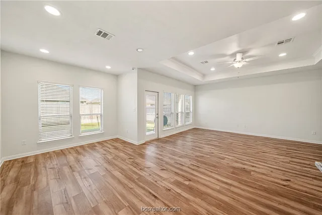a view of an empty room with a window and wooden floor