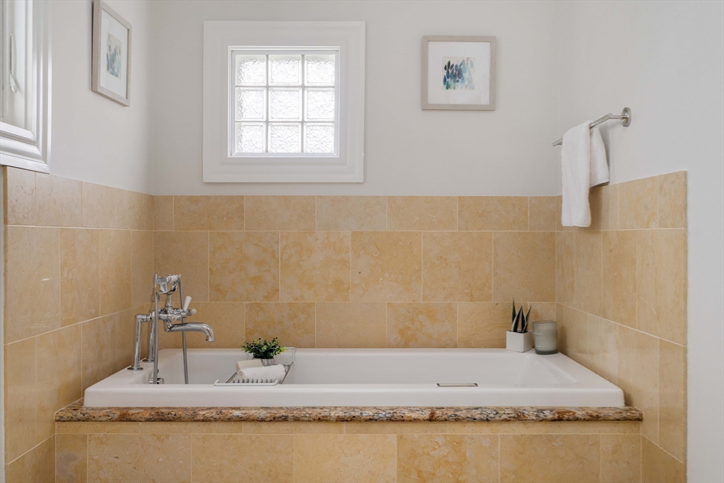 18-20 Windom Street Somerville, MA 02144 - Photo 22 of 34 a bathroom with a granite countertop sink a bathtub and a window