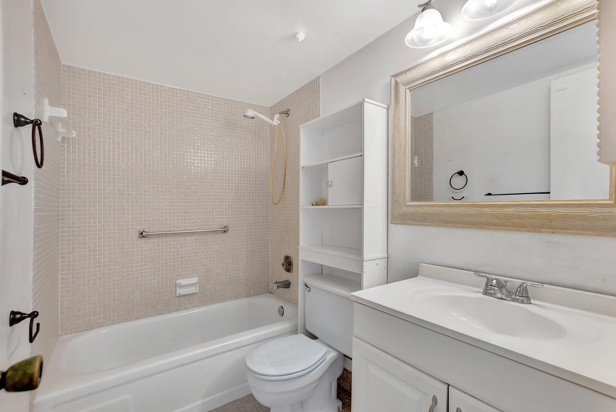 147 Brighton D, Unit D Boca Raton, FL 33434 - Photo 12 of 50 a bathroom with a granite countertop bathtub shower sink vanity mirror and toilet