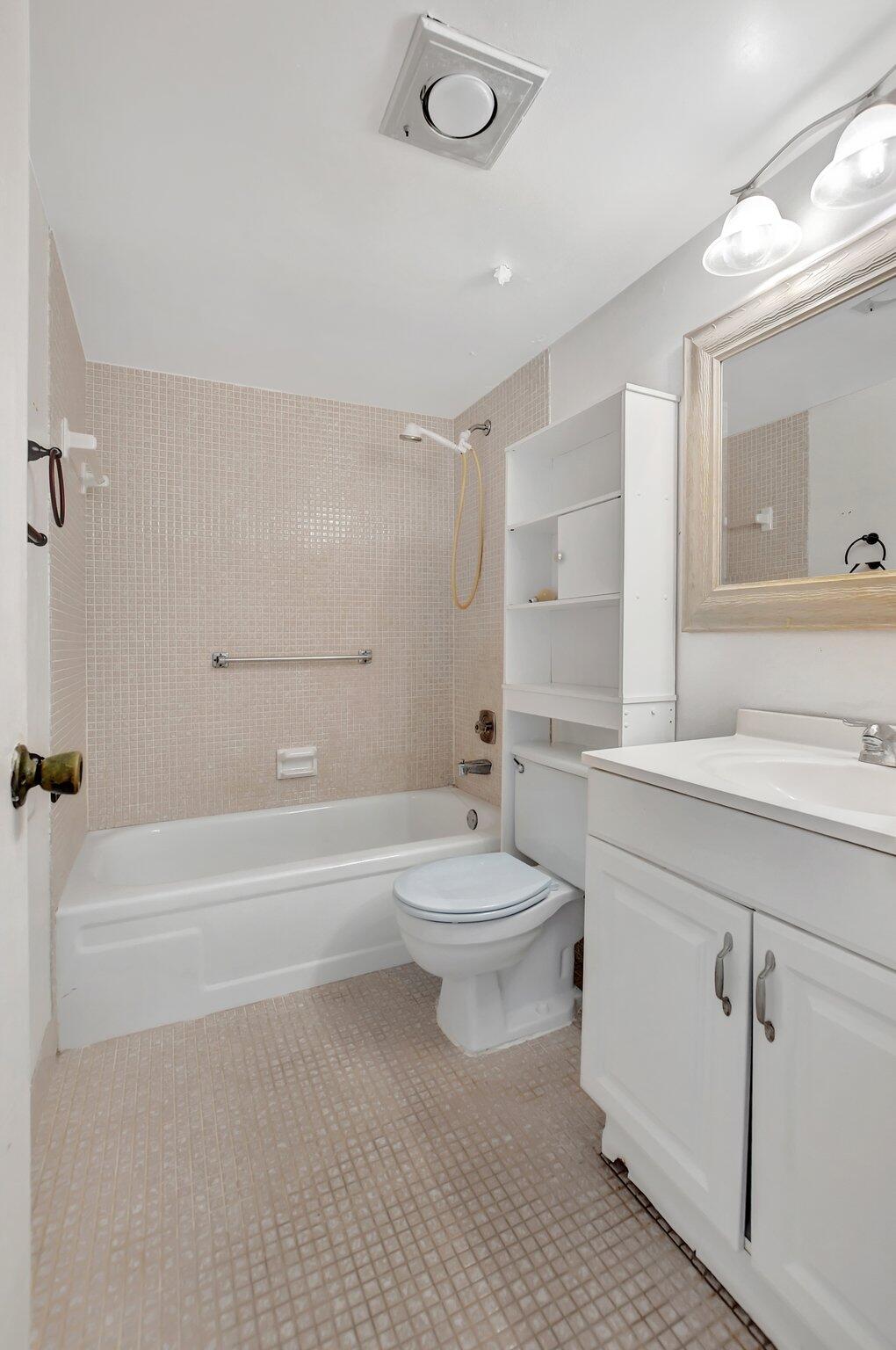 147 Brighton D, Unit D Boca Raton, FL 33434 - Photo 14 of 50 a bathroom with a toilet a sink a mirror and bathtub