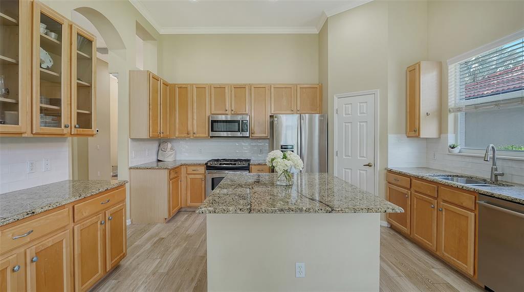 7717 US Open Loop Lakewood Ranch, FL 34202 - Photo 10 of 95 a kitchen with kitchen island granite countertop a sink stove refrigerator and cabinets