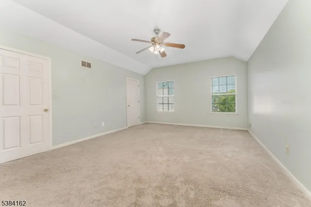 an empty room with windows and ceiling fan