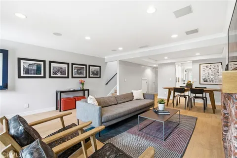 a living room with furniture and a dining table with wooden floor