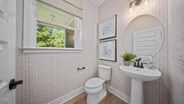 a bathroom with a sink a mirror a toilet and a window