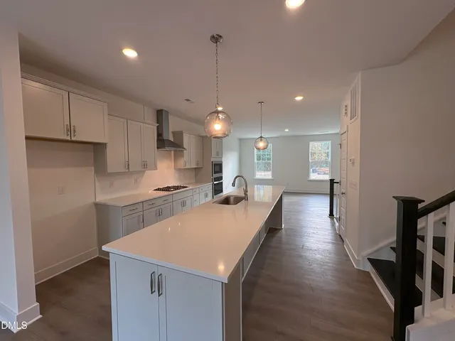 a large kitchen with kitchen island a stove a sink a center island and wooden floor