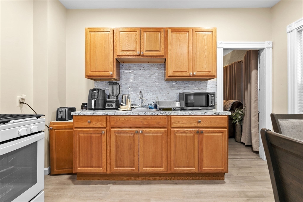 132 Vernal Street Everett, MA 02149 - Photo 15 of 22 a kitchen with stainless steel appliances granite countertop a refrigerator a sink dishwasher a stove top oven a dining table and chairs with wooden floor