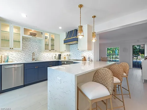 a kitchen with stainless steel appliances granite countertop a sink dishwasher a stove a refrigerator with island and chairs