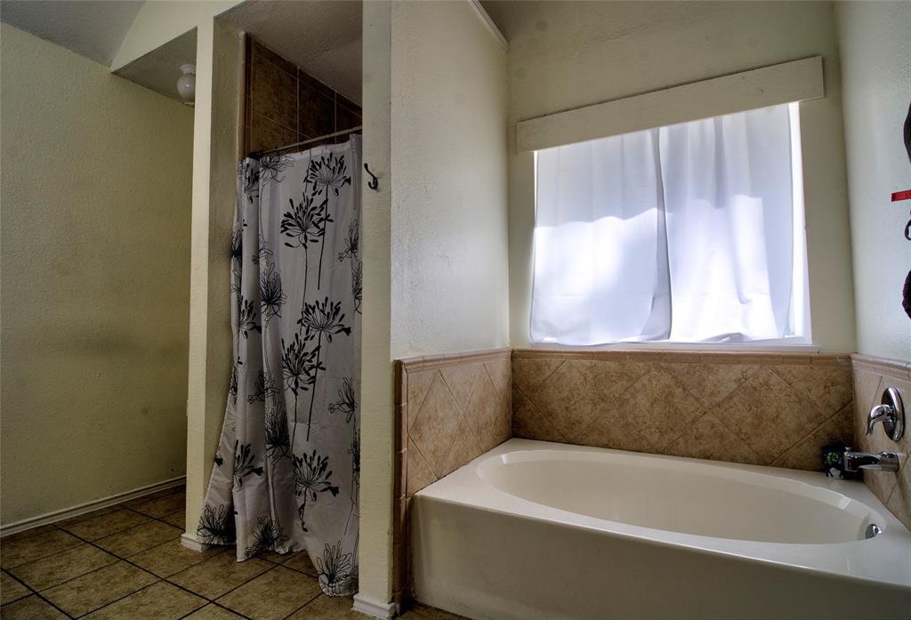 4825 Bobtown Road Garland, TX 75043 - Photo 11 of 17 a bathroom with a bathtub and a shower
