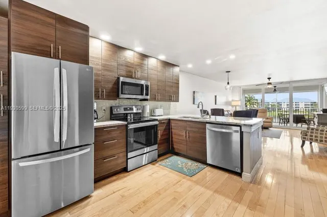 a kitchen with stainless steel appliances granite countertop a refrigerator a stove top oven a sink dishwasher and white cabinets with wooden floor