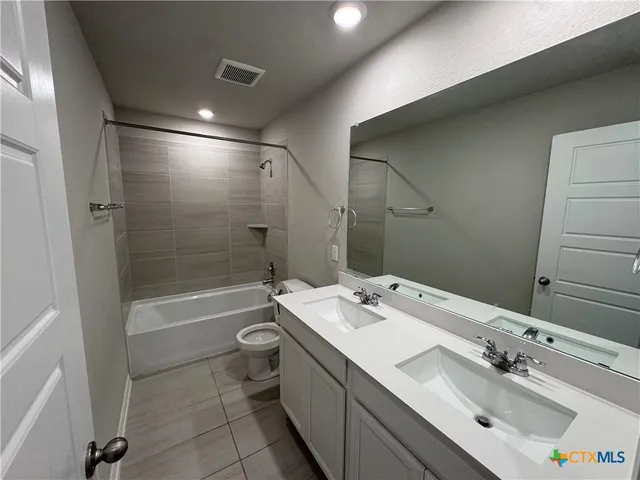 a bathroom with a tub sink mirror and toilet