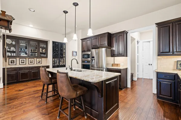 a kitchen with stainless steel appliances kitchen island granite countertop a table chairs and a refrigerator