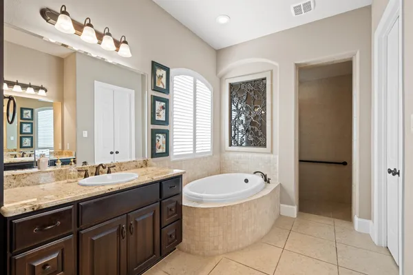 a bathroom with a tub sink double vanity and mirror