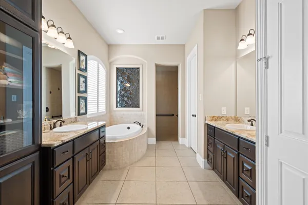 a spacious bathroom with a double vanity sink a large mirror and a bathtub