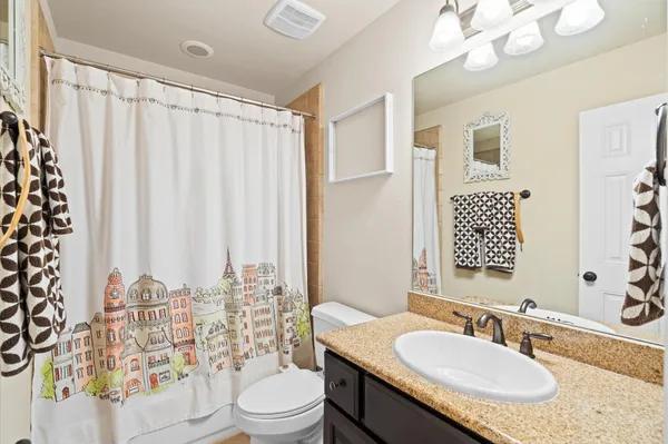 a bathroom with a granite countertop sink a toilet and a mirror
