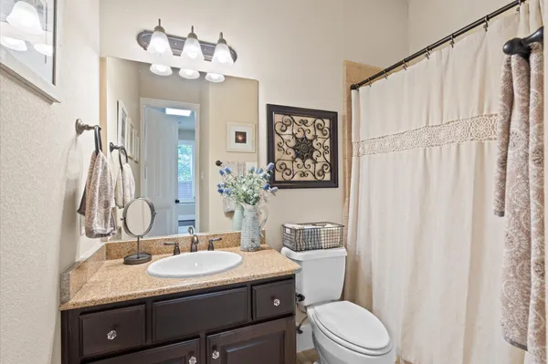 a bathroom with a granite countertop sink toilet a mirror and shower curtain