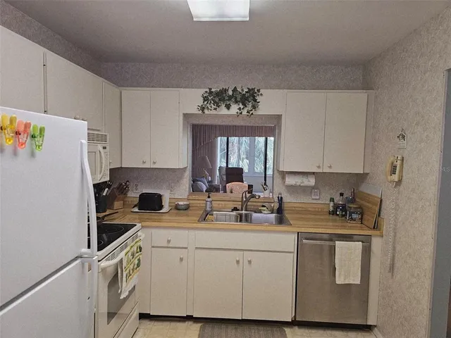 a kitchen with white cabinets white appliances and sink