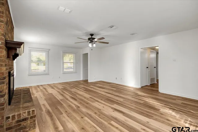 a view of empty room with wooden floor and ceiling fan