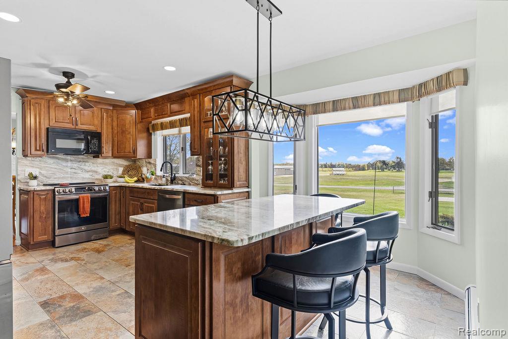 8742 Hyne Road Brighton, MI 48114 - Photo 18 of 65 Kitchen with light stone countertops, stainless steel appliances, stone tile floors, pendant lighting, and a breakfast bar area