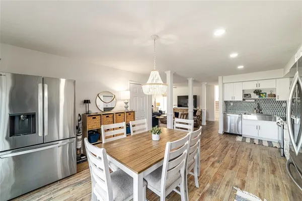 a kitchen with stainless steel appliances granite countertop a refrigerator a oven a sink a dining table and chairs with wooden floor