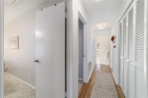 a view of a hallway with wooden floor and closet