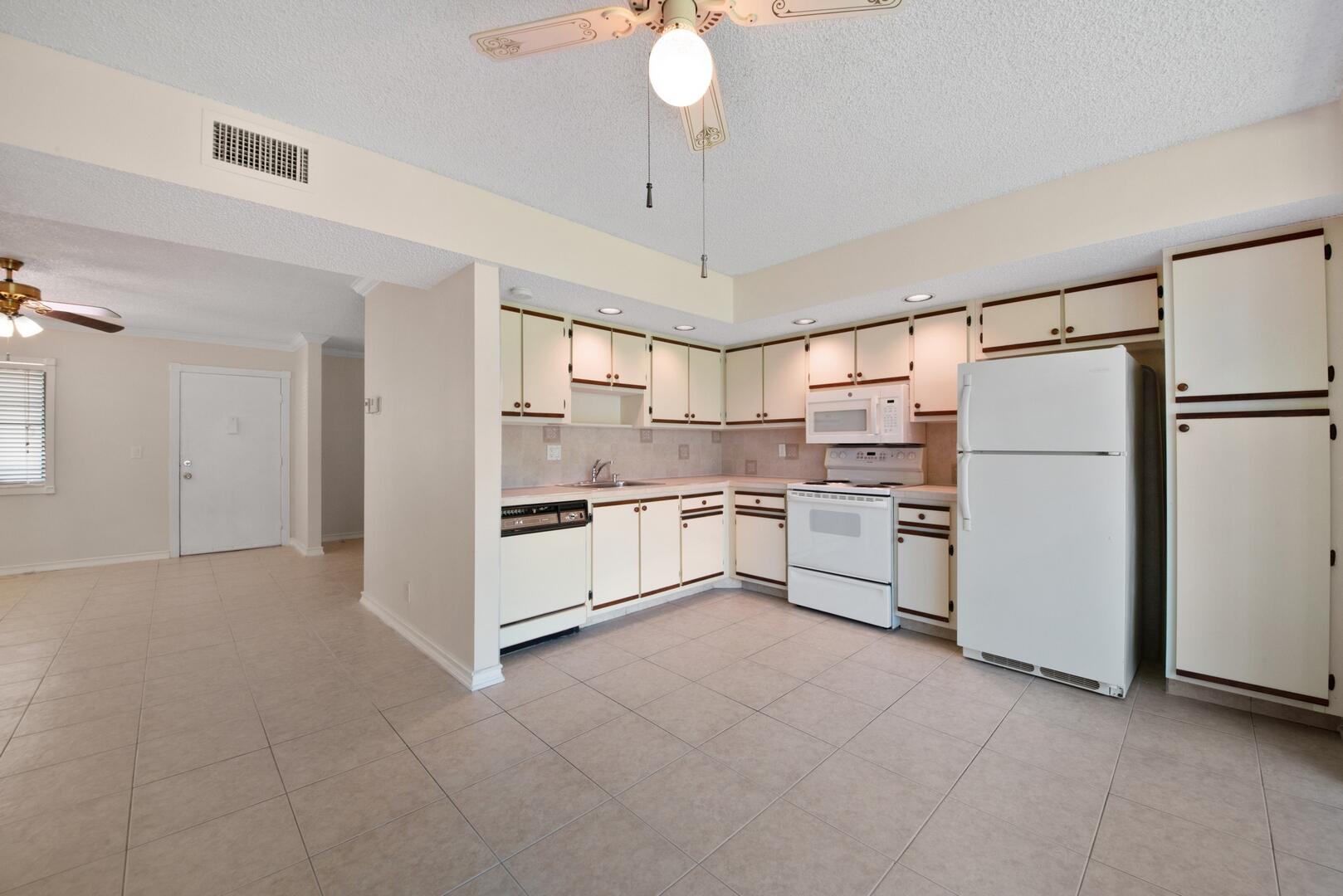 5310 Las Verdes Circle, Unit 118 Delray Beach, FL 33484 - Photo 6 of 20 a kitchen with white cabinets and white appliances