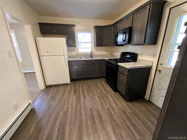 a kitchen with a refrigerator a stove top oven a sink and dishwasher with wooden floor