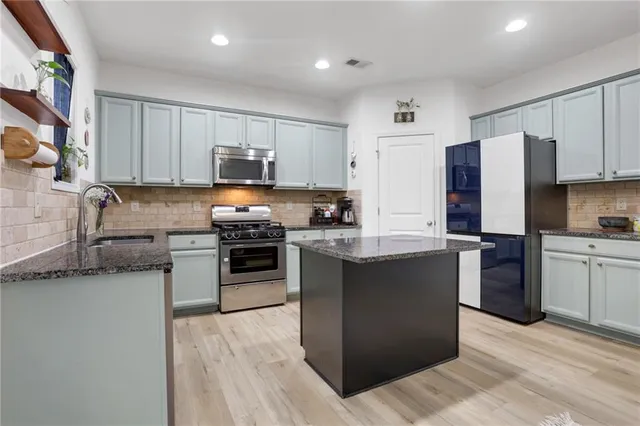 a kitchen with granite countertop a refrigerator and a stove top oven