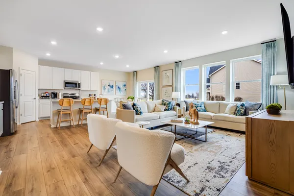 a living room with furniture and kitchen view with wooden floor