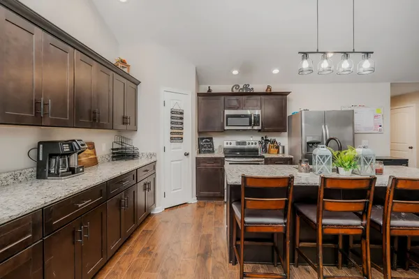 a kitchen with kitchen island granite countertop stainless steel appliances cabinets a dining table and chairs