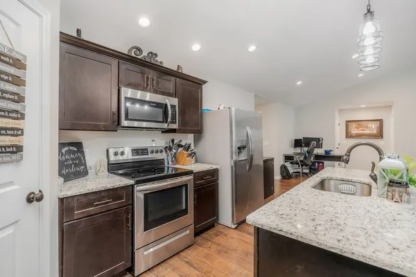 a kitchen with stainless steel appliances kitchen island granite countertop a stove refrigerator and microwave