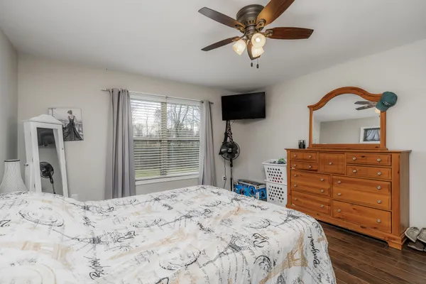 a bedroom with a bed a dresser and flat screen tv