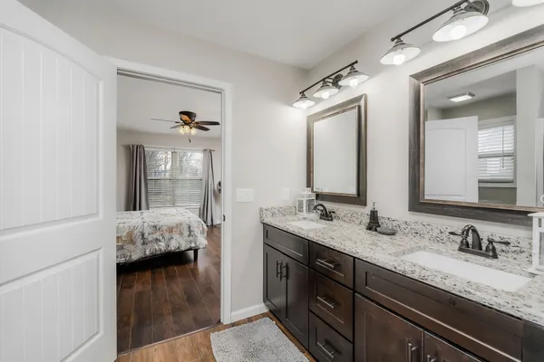 a en suite bathroom with a granite countertop double vanity sink and a mirror