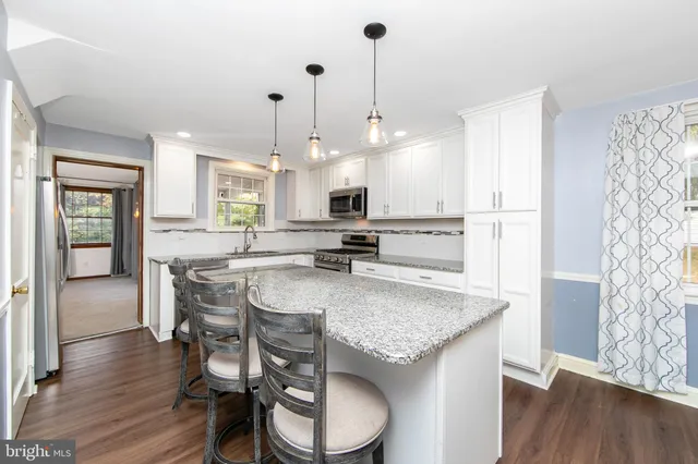 a kitchen with stainless steel appliances granite countertop a stove a sink dishwasher a dining table and chairs with wooden floor