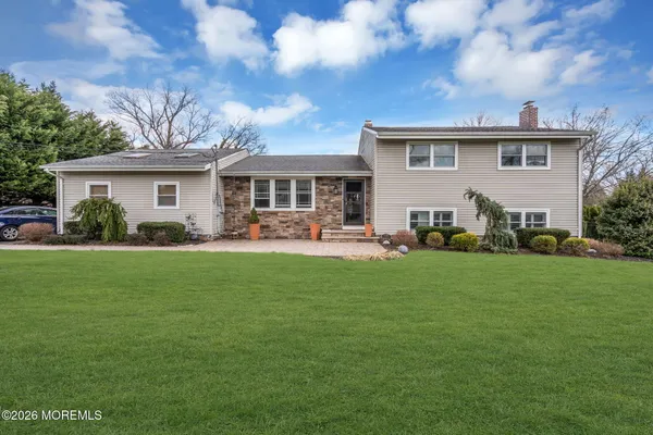 a front view of a house with a garden and trees