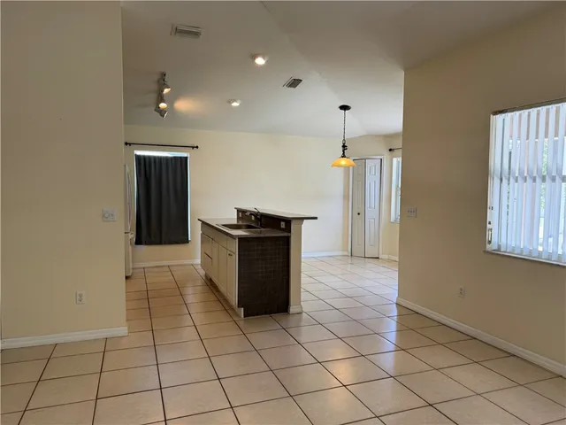 an empty room & kitchen space with wooden floor