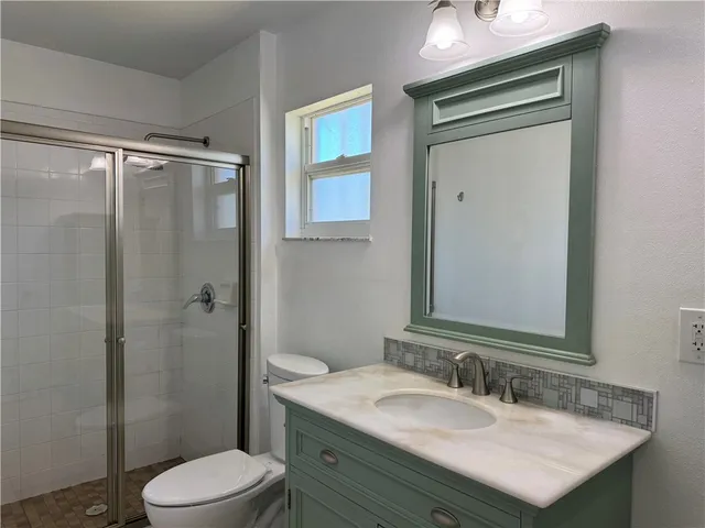 a bathroom with a granite countertop sink toilet a mirror a vanity and shower