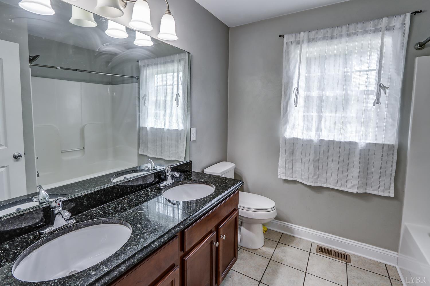 1057 Old Trail Road Forest, VA 24551 - Photo 30 of 49 a bathroom with a granite countertop double vanity sink a mirror and a toilet