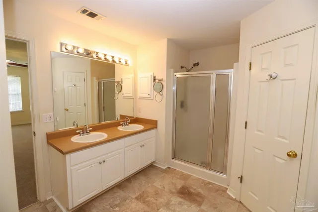 a bathroom with a granite countertop sink a mirror and a shower