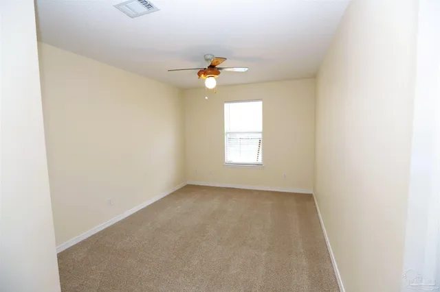 an empty room with windows and fan