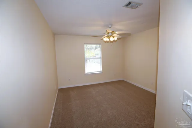 an empty room with windows and ceiling fan