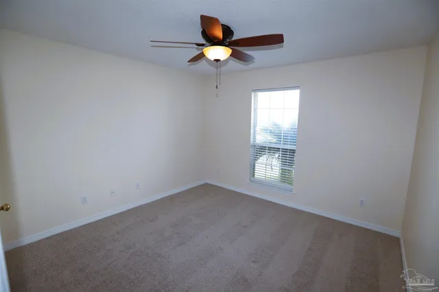 an empty room with a window and a ceiling fan