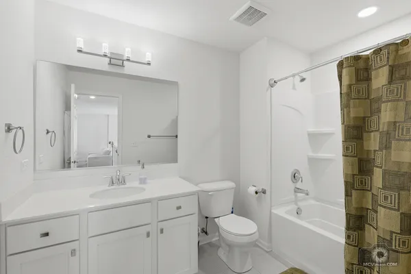 a bathroom with a double vanity sink toilet mirror and bathtub
