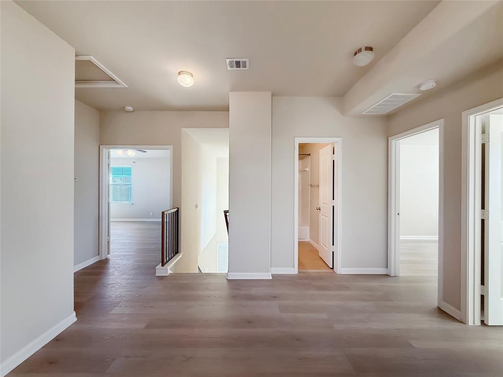 8505 Inca Dove Drive Austin, TX 78729 - Photo 15 of 30 Spacious landing area featuring light wood flooring, several doorways, and a staircase with a dark wood and metal railing