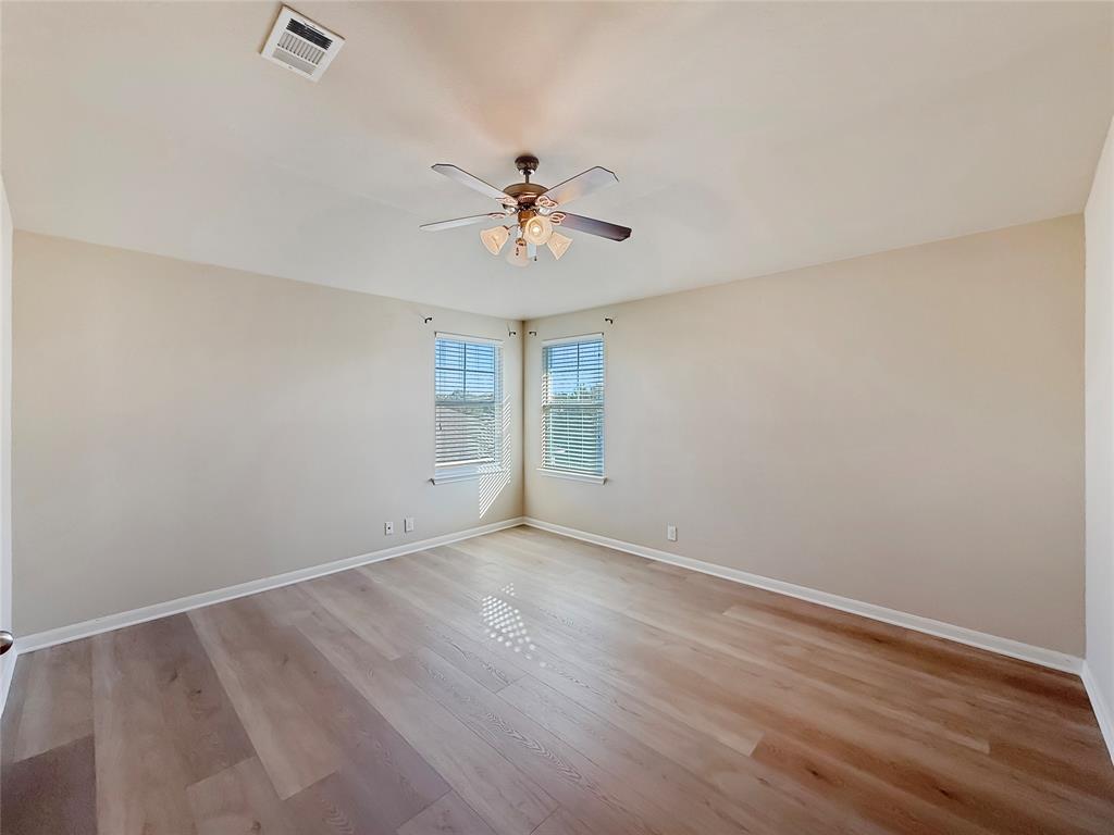 8505 Inca Dove Drive Austin, TX 78729 - Photo 17 of 30 Bright room featuring light-colored walls, light wood-style flooring, and two windows with blinds