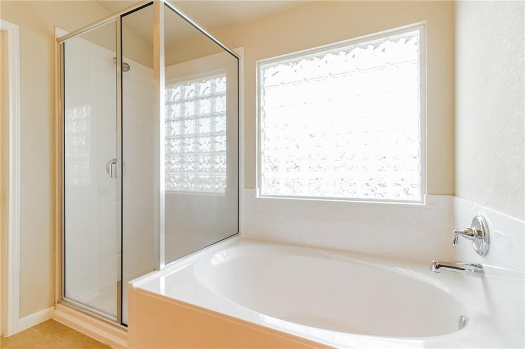 8505 Inca Dove Drive Austin, TX 78729 - Photo 21 of 30 Bathroom featuring a built-in bathtub with chrome fixtures and a glass-enclosed shower