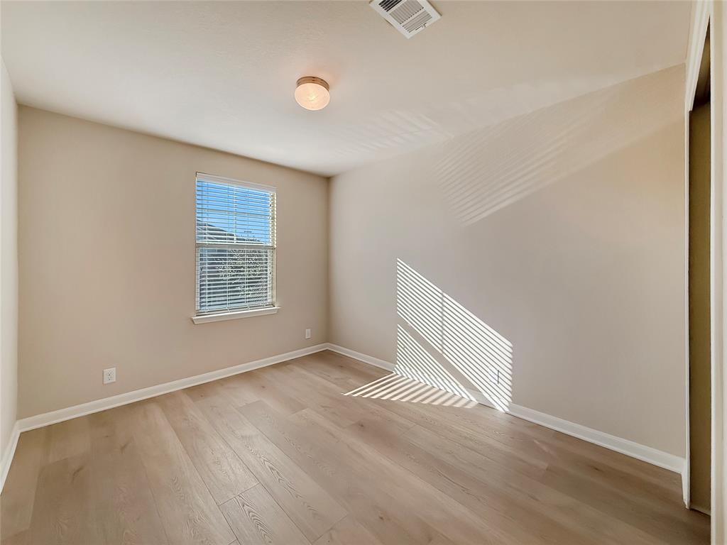 8505 Inca Dove Drive Austin, TX 78729 - Photo 22 of 30 Room featuring light-colored walls, light wood flooring, a window with blinds, and an overhead light fixture